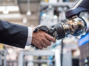 Mano humana estrechando la mano de un robot industrial
