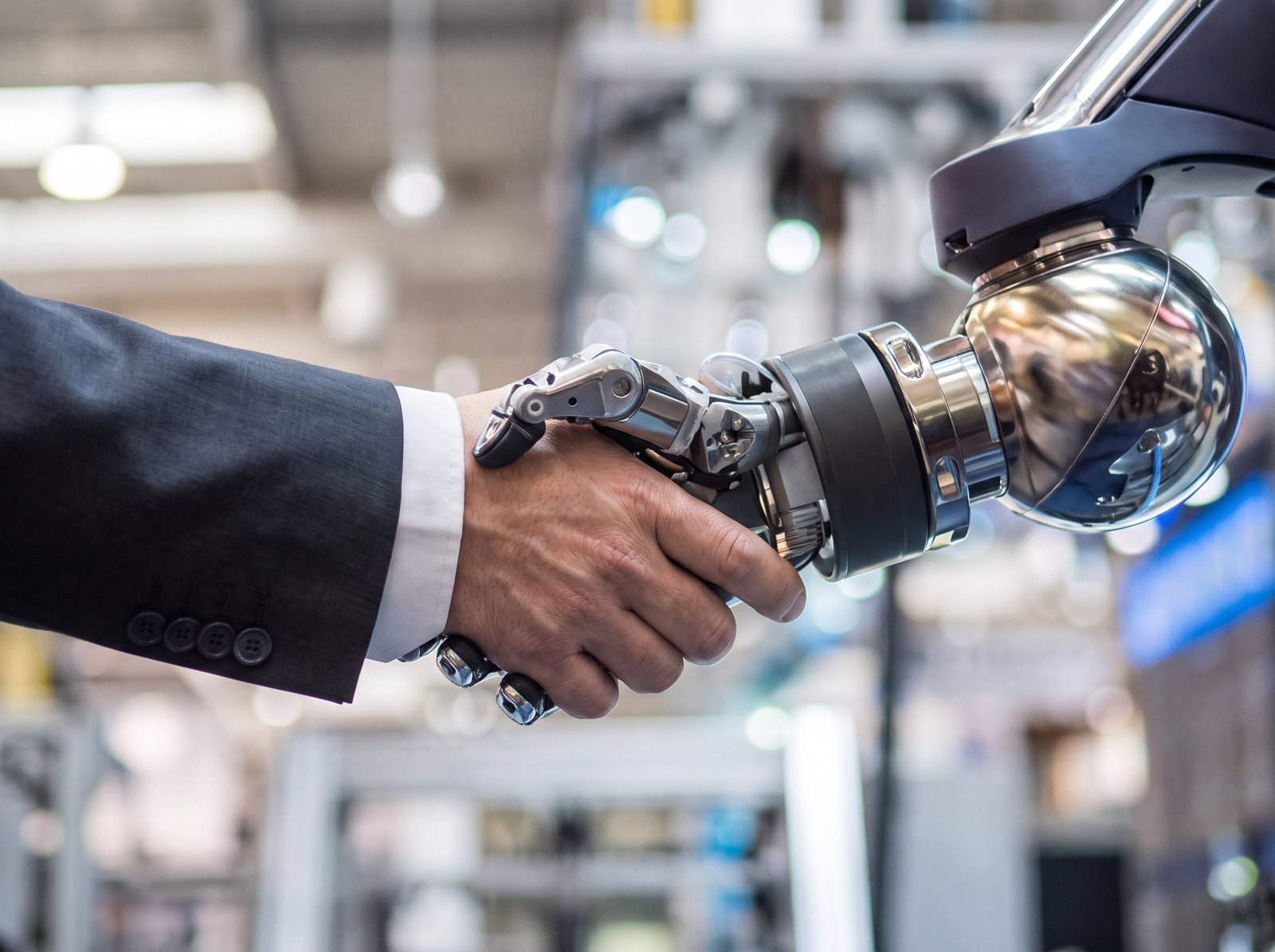 Mano humana estrechando la mano de un robot industrial